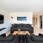 Wohnzimmer mit Sofa, Fernseher und Tisch. Hintergrund zeigt Flur und Schrank.