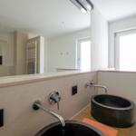 Badezimmer mit zwei schwarzen Waschbecken, Spiegel und Fenster.