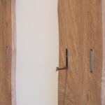 Zwei Holztüren mit metallischen Griffen an einer weißen Wand.