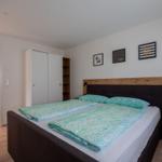 Schlafzimmer mit Doppelbett, Kleiderschrank und Wandbildern.