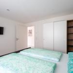 Schlafzimmer mit Doppelbett, Schrank und Wandfernseher