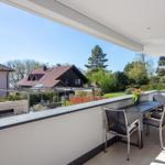 Terrasse mit Tisch und Stühlen, Blick auf Garten und Nachbarhäuser.