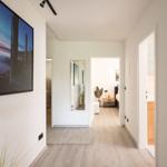 Flur mit Wandbild, Spiegel und Blick in Schlaf- und Badezimmer.