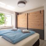 Schlafzimmer mit Doppelbett, Holzwand und Fenster mit Blick auf Bäume.