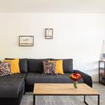 Schwarzer Sofa mit Kissen, Holztisch und Wanddekoration im Wohnzimmer.