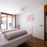 Schlafzimmer mit Bett, Balkon und Blick in Wohnzimmer