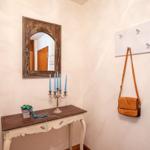 Hausflur mit Spiegel, Tisch, Kerzen und Handtasche an Wandhalterung.