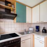 Küche mit Dunstabzug, Herd, Spüle und Kühlschrank.