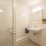 Badezimmer mit Dusche, Waschbecken und Heizkörper