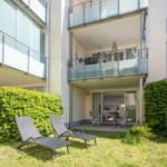 Hinterhof mit Liegestühlen und Balkon. Küche und Essbereich sind sichtbar.