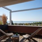 Terrasse mit Liegestühlen und Blick auf See und Landschaft.