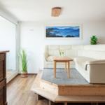Wohnzimmer mit weißem Sofa, Holztisch und Blick auf Balkon.