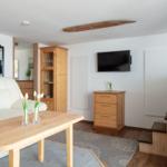 Wohnzimmer mit Sofa, Tisch, Fernseher und Holzmöbeln.