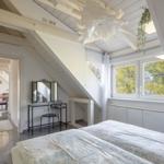 Schlafzimmer mit Dachschrägen, Fenster und Schminktisch. Blick in das angrenzende Wohnzimmer.