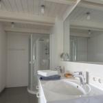 Badezimmer mit Dusche, Waschbecken und Spiegel