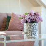 Ein Glas-Tisch mit Blumenkorb und Sofa im Hintergrund.