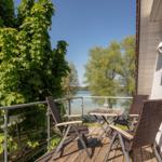 Terrasse mit Tisch und Stühlen, Blick auf Wasser und Bäume.