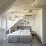 Schlafzimmer mit Dachschräge, Bett, Fenster und Schränken.