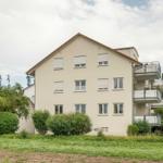Ein Mehrfamilienhaus mit Balkonen und grüner Umgebung.
