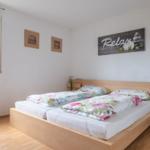Schlafzimmer mit Doppelbett, Fenster und Wandbild mit Relax.