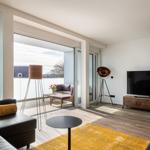 Wohnzimmer mit Balkon, Sofa, Fernseher und Holzmöbel.
