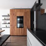 Moderne Küche mit Holzschränken, schwarzer Arbeitsplatte und integriertem Backofen.