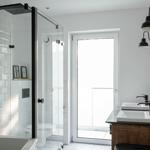 Badezimmer mit Dusche, Waschbecken und Toilette. Weiße Fliesen und schwarze Armaturen.