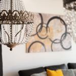 Ein Raum mit einer Kronleuchter und einem Wandbild über einem Sofa.
