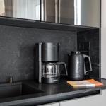 Küchenbereich mit Kaffeemaschine und Wasserkocher auf dunkler Arbeitsplatte.