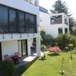 Moderne Villa mit Balkon, Garten und Sitzgelegenheiten.