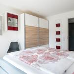 Schlafzimmer mit Bett, Kleiderschrank und Wandregalen.