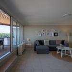 Wohnbereich mit Sofa, Couchtisch und Blick auf Terrasse mit Tisch und Stühlen.