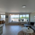 Wohnzimmer mit Sofa, TV und Blick auf Terrasse mit Gartenansicht.