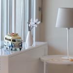 Auf dem Fensterbrett steht ein Modellbus mit Surfbrett, daneben ein Vasen mit Blumen und eine Lampe.