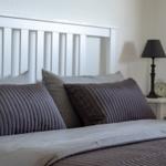 Doppelbett mit Kopfkissen und Nachttisch mit Lampe und Wecker