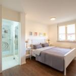 Schlafzimmer mit Doppelbett und angrenzender Dusche.