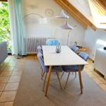 Essbereich mit Tisch, Stühlen und Sitzgelegenheit. Dachgeschoss mit Holzkonstruktion und Fenster.