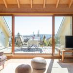 Wohnraum mit Balkon, Fernseher und Sitzgelegenheiten.