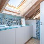 Badezimmer mit Dachschrägen, Glasarbeitsplatte und Mosaikwand