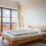Schlafzimmer mit Holzbett und Balkonblick. Holzfußboden und Nachttisch.