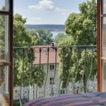 Von Balkon mit Eisengeländer Blick auf See und grüne Bäume.