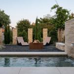 Pool mit Wasserfall, Liegen und Feuerstelle im Garten