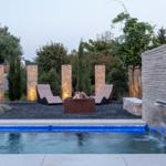 Pool mit Wasserfall, Liegestühle und Feuerkorb im Garten.