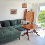Grünes Sofa, Holztisch und Garderobe im Wohnbereich mit Blick auf Balkon.