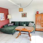 Ein Wohnzimmer mit grünem Sofa, Holztisch und antikem Schrank.