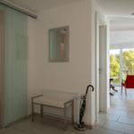 Flur mit Badezimmer und Blick auf Wohnbereich mit rotem Sessel.