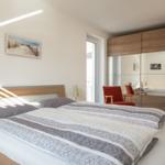 Schlafzimmer mit Doppelbett, Spiegelschrank und Fenster zum Balkon.