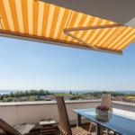 Terrasse mit orangefarbenem Markisenüberdachung, Tisch und Stühle mit Blick auf Landschaft.