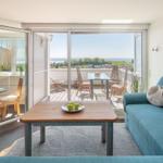 Wohnzimmer mit blauem Sofa und Balkonblick auf See