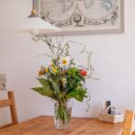 Esstisch mit Blumenarrangement, Holzstühle und Wandbild mit Weltkarte.